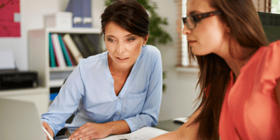Two woman looking at a computer in an office. 